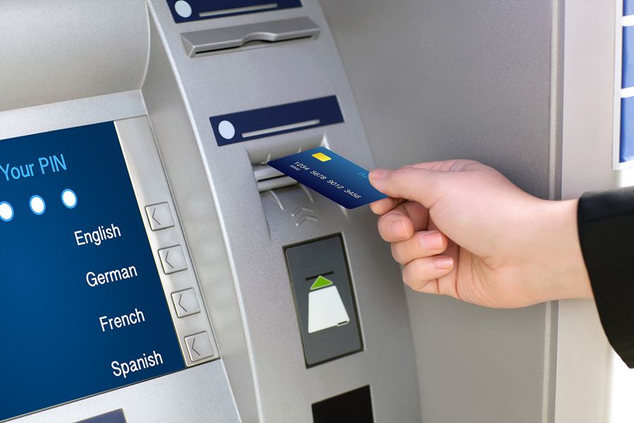 person inserting a debit card into an ATM
